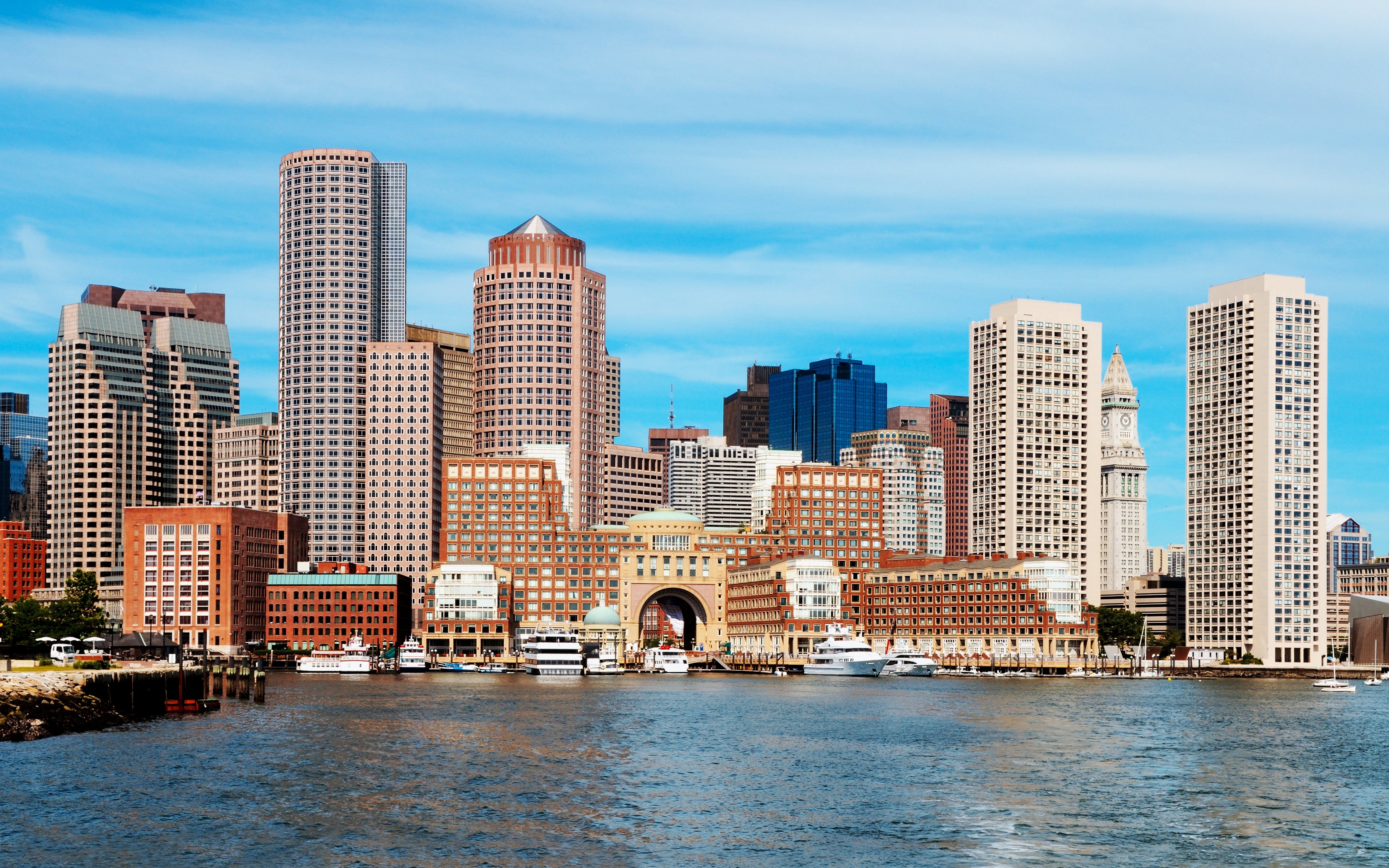 Boston skyline viewed from the harbor with prominent skyscrapers and waterfront.