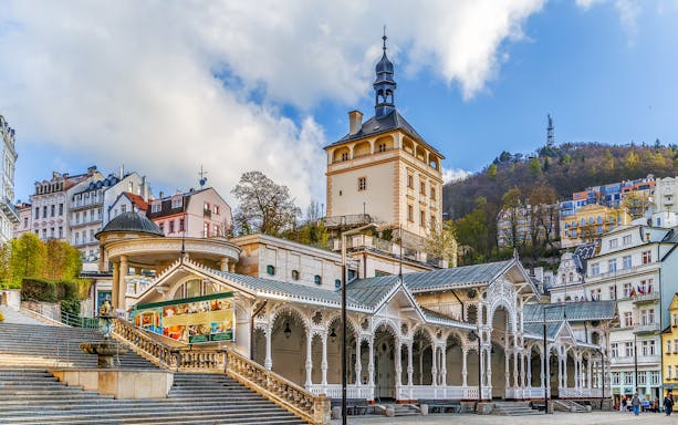 Karlovy Vary colonnade and historic buildings with Watchtower Diana in the background.