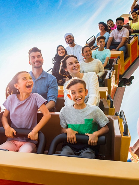 Kids and adults on a roller coaster at a Dubai theme park.