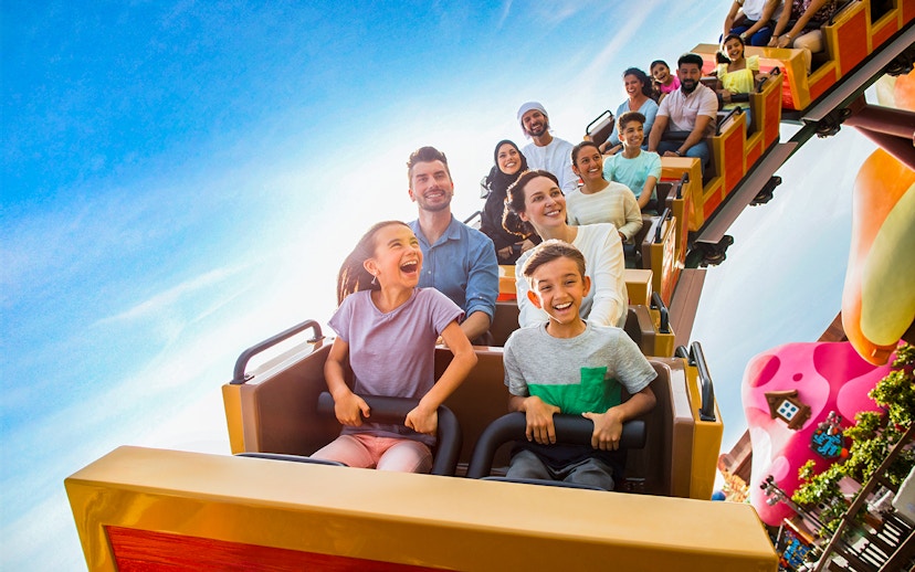 Kids and adults on a roller coaster at a Dubai theme park.