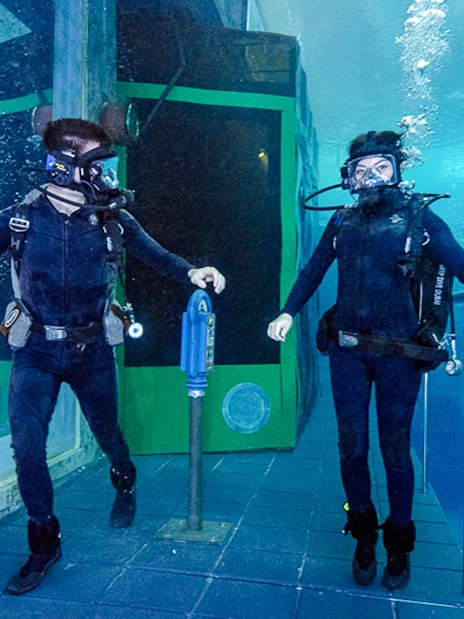 Divers exploring underwater Sunken City attraction.