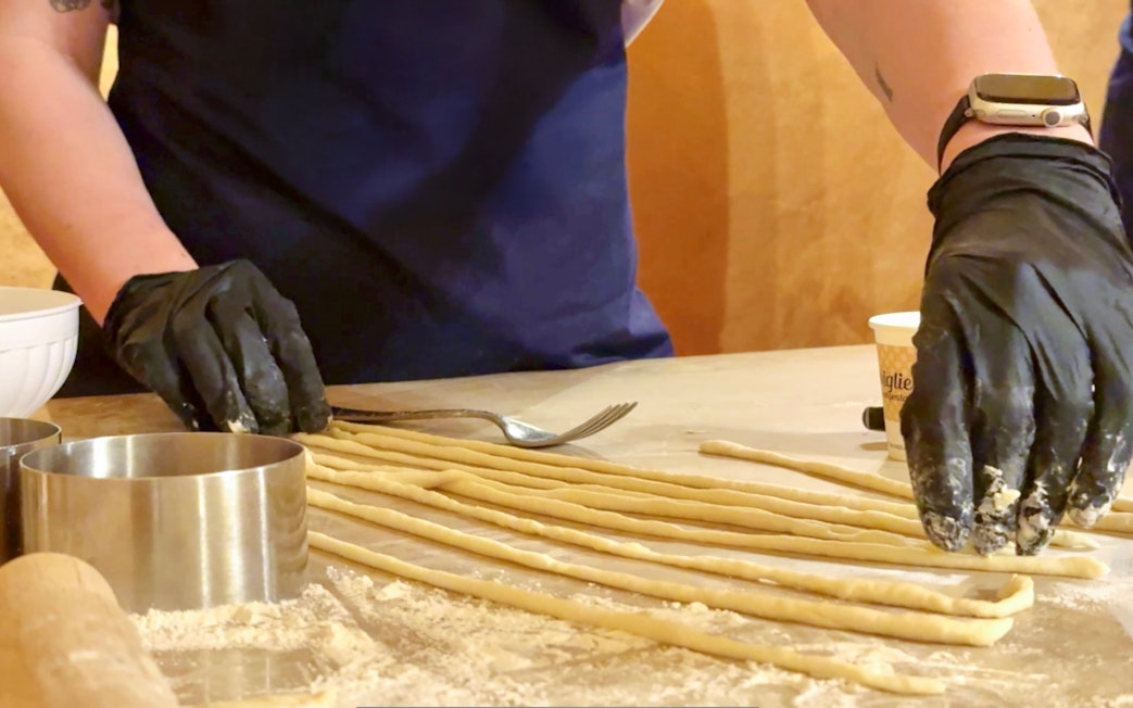 Participant preparing pasta during cooking class in Siena.