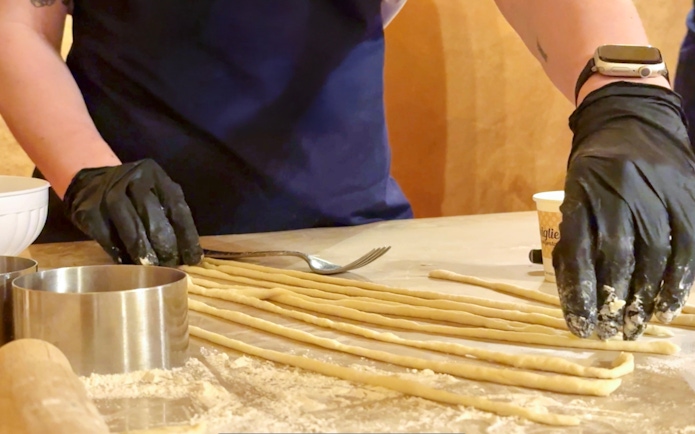 Participant preparing pasta during cooking class in Siena.