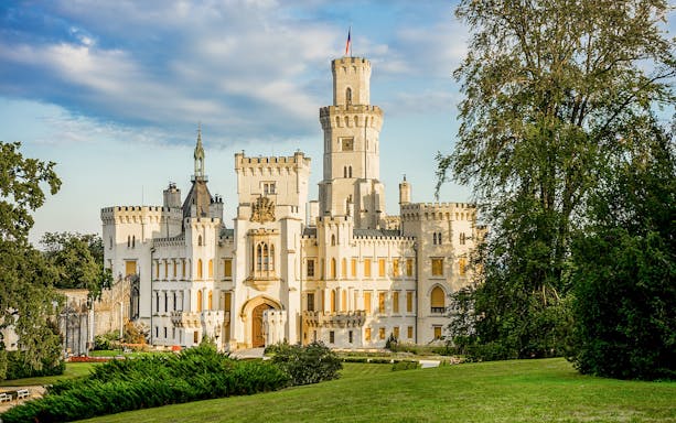 Hluboká Castle in the Czech Republic with lush gardens and a clear sky.