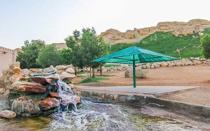 Waterfall and green umbrella at Al Ain heritage site during city tour from Dubai.