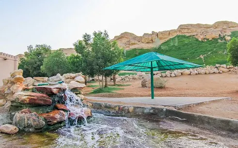 Waterfall and green umbrella at Al Ain heritage site during city tour from Dubai.