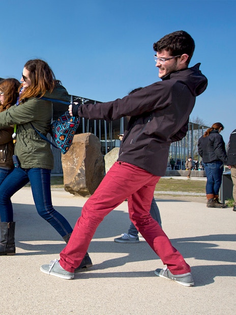 Visitors pulling a rope to move a large stone at Stonehenge exhibit, England.