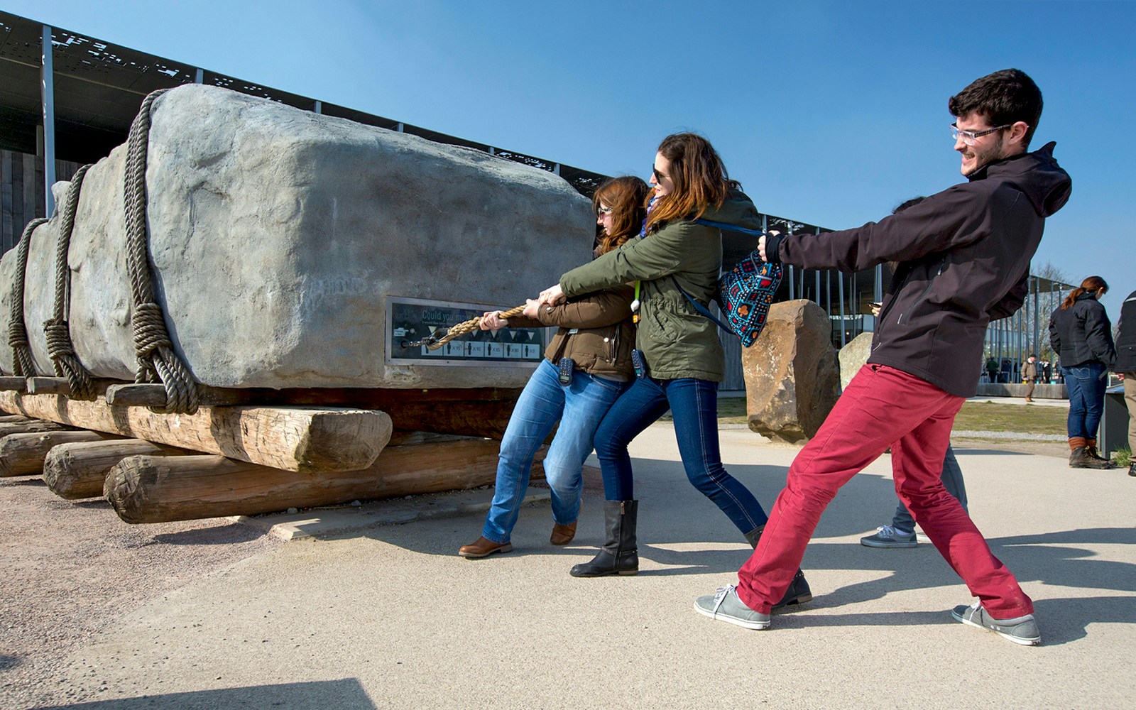 Visitors pulling a rope to move a large stone at Stonehenge exhibit, England.