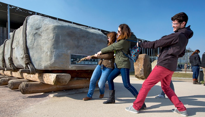 Visitors pulling a rope to move a large stone at Stonehenge exhibit, England.