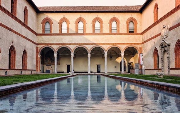 Sforza Castle courtyard with arches and reflecting pool, Milan, Italy.