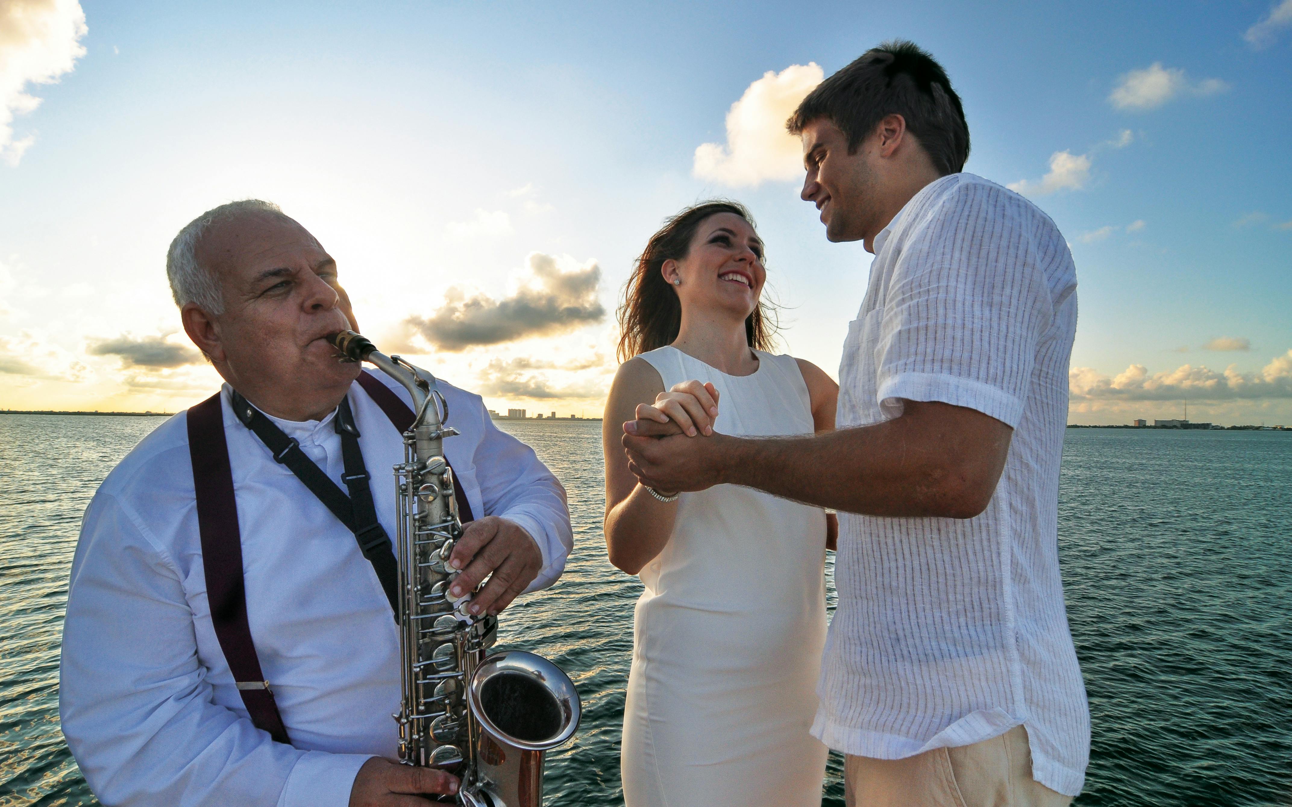Couple dancing with saxophonist on sunset cruise in Cancun.