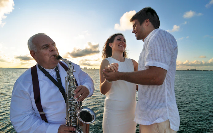 Couple dancing with saxophonist on sunset cruise in Cancun.