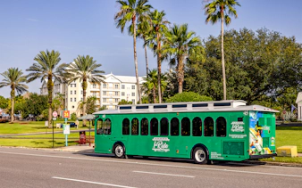 Orlando I-Ride trolley bus parked near palm trees and a residential building.