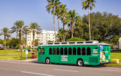Orlando I-Ride trolley bus parked near palm trees and a residential building.