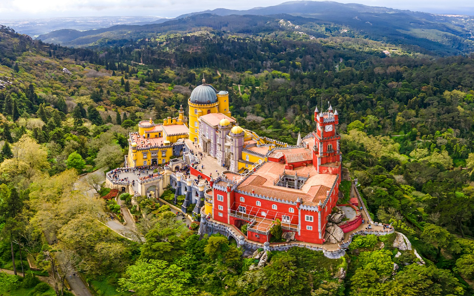 Aerial view of the colorful National Palace of Pena surrounded by lush greenery in Sintra, Portugal.