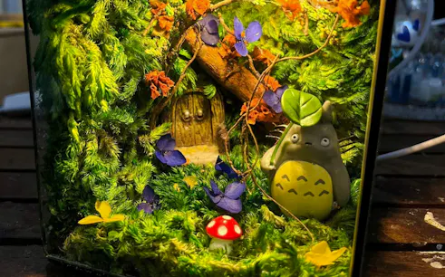 Miniature garden terrarium with figurine, moss, and colorful flowers, Hanoi.