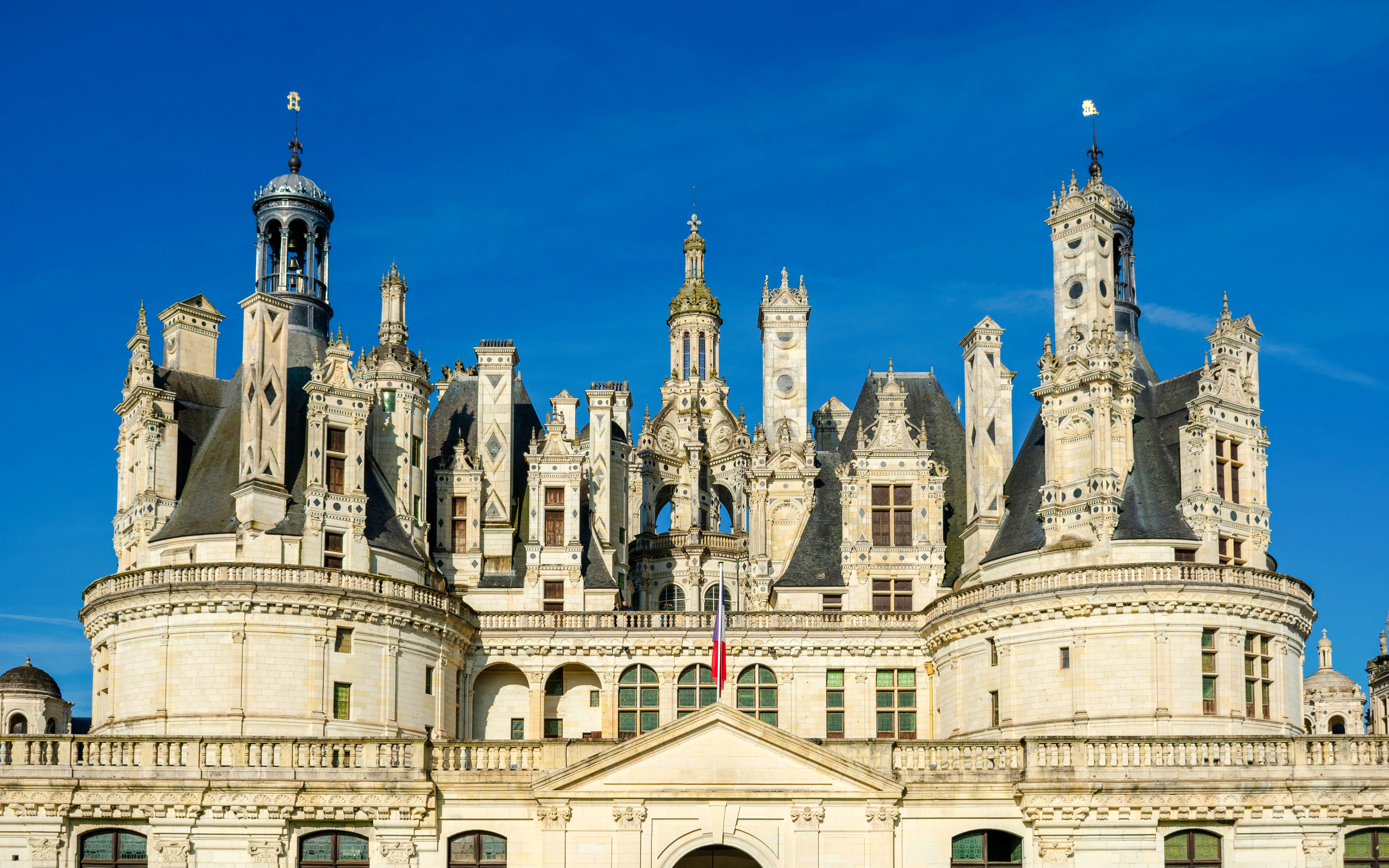 Chambord Castle facade with ornate towers and blue sky, France.