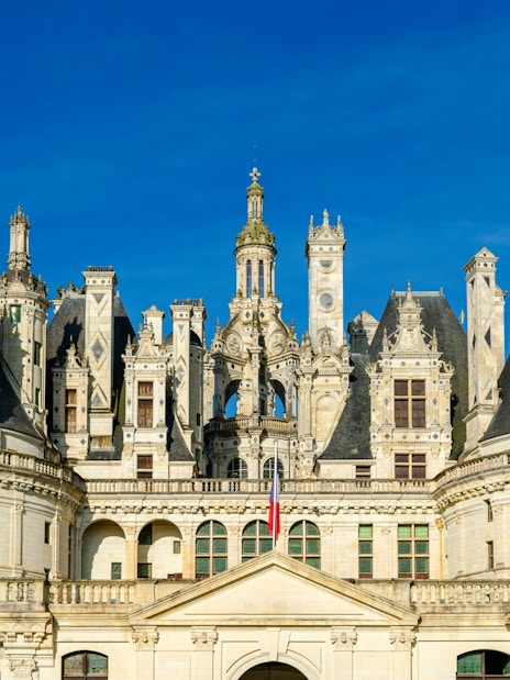 Chambord Castle facade with ornate towers and blue sky, France.