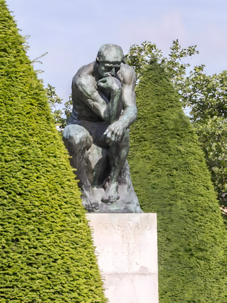 The Thinker sculpture at Rodin Museum surrounded by greenery.