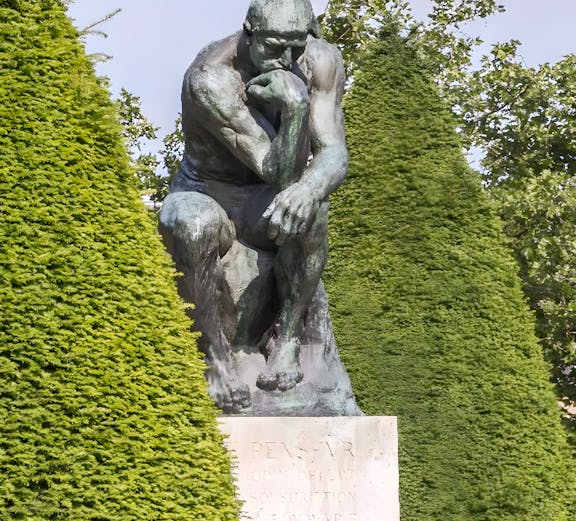 The Thinker sculpture at Rodin Museum surrounded by greenery.