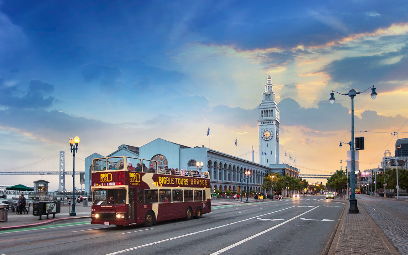 Big Bus passing San Francisco Ferry Building during sunset tour.