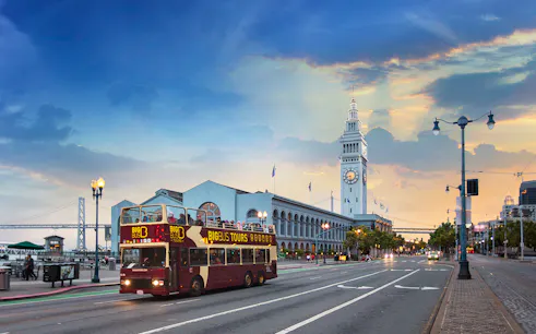 Big Bus passing San Francisco Ferry Building during sunset tour.