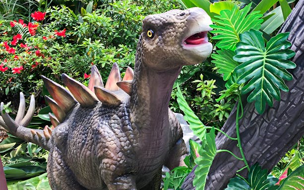 Dinosaur statue in lush greenery at Dino Park Yanbaru, Okinawa.