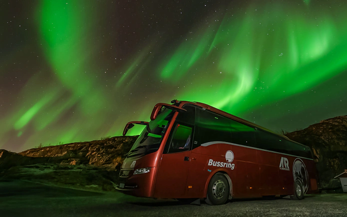 Bus under Northern Lights during Aurora chase in Tromsø.