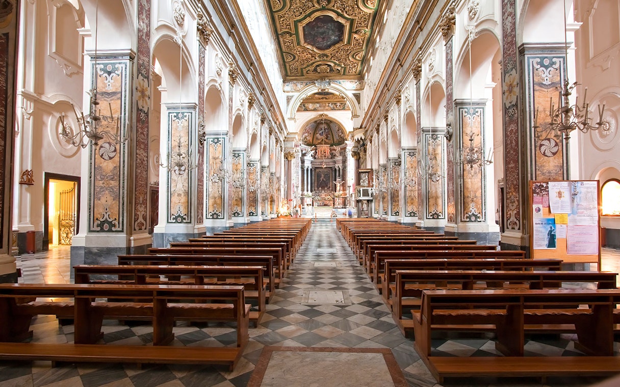 Interior of Amalfi Cathedral with ornate columns and wooden pews, Amalfi Coast.
