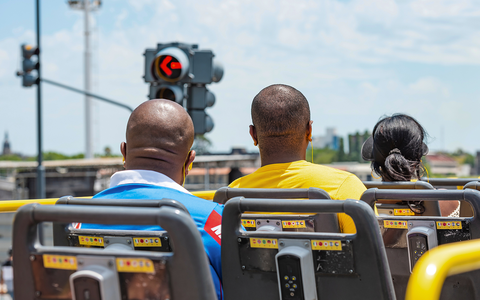 Back view of tourists, two man and a women rides on a double decker bus for sightseeing, sunny day