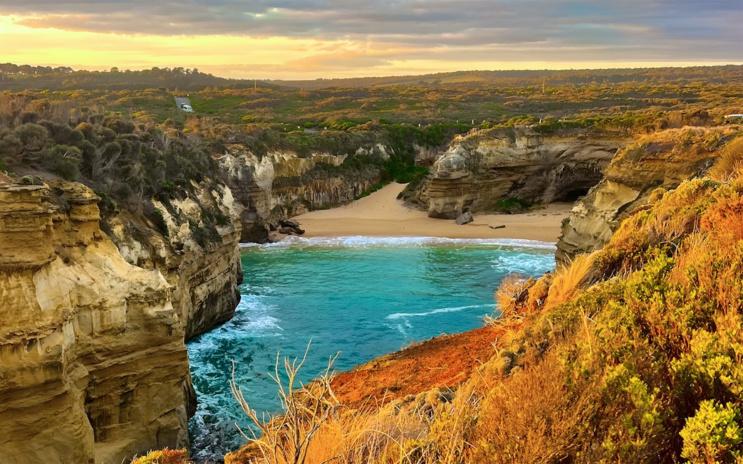 Loch Ard Gorge at sunset, Great Ocean Road tour, featuring cliffs and turquoise water.