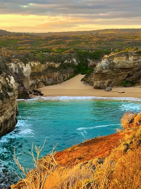 Loch Ard Gorge at sunset, Great Ocean Road tour, featuring cliffs and turquoise water.