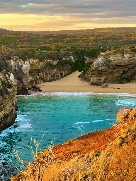 Loch Ard Gorge at sunset, Great Ocean Road tour, featuring cliffs and turquoise water.