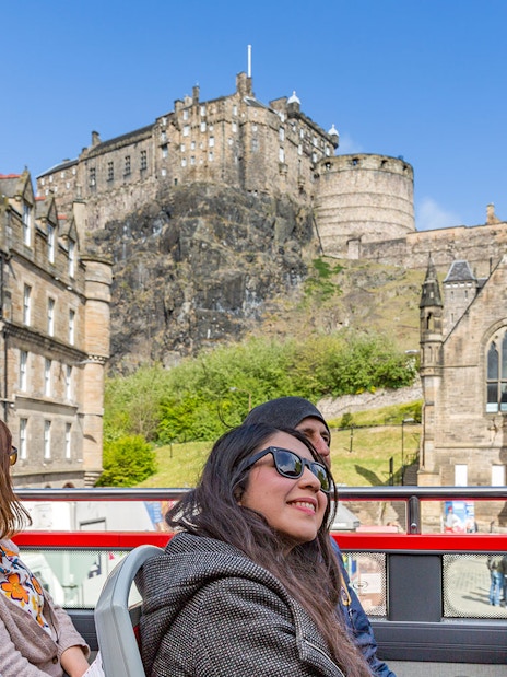 Edinburgh Castle viewed from a hop-on hop-off tour bus with tourists.