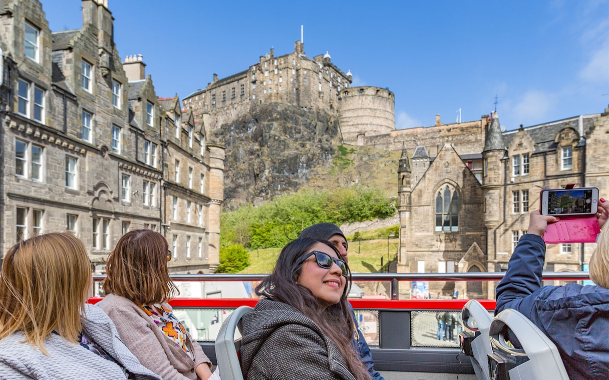 Edinburgh Castle viewed from a hop-on hop-off tour bus with tourists.