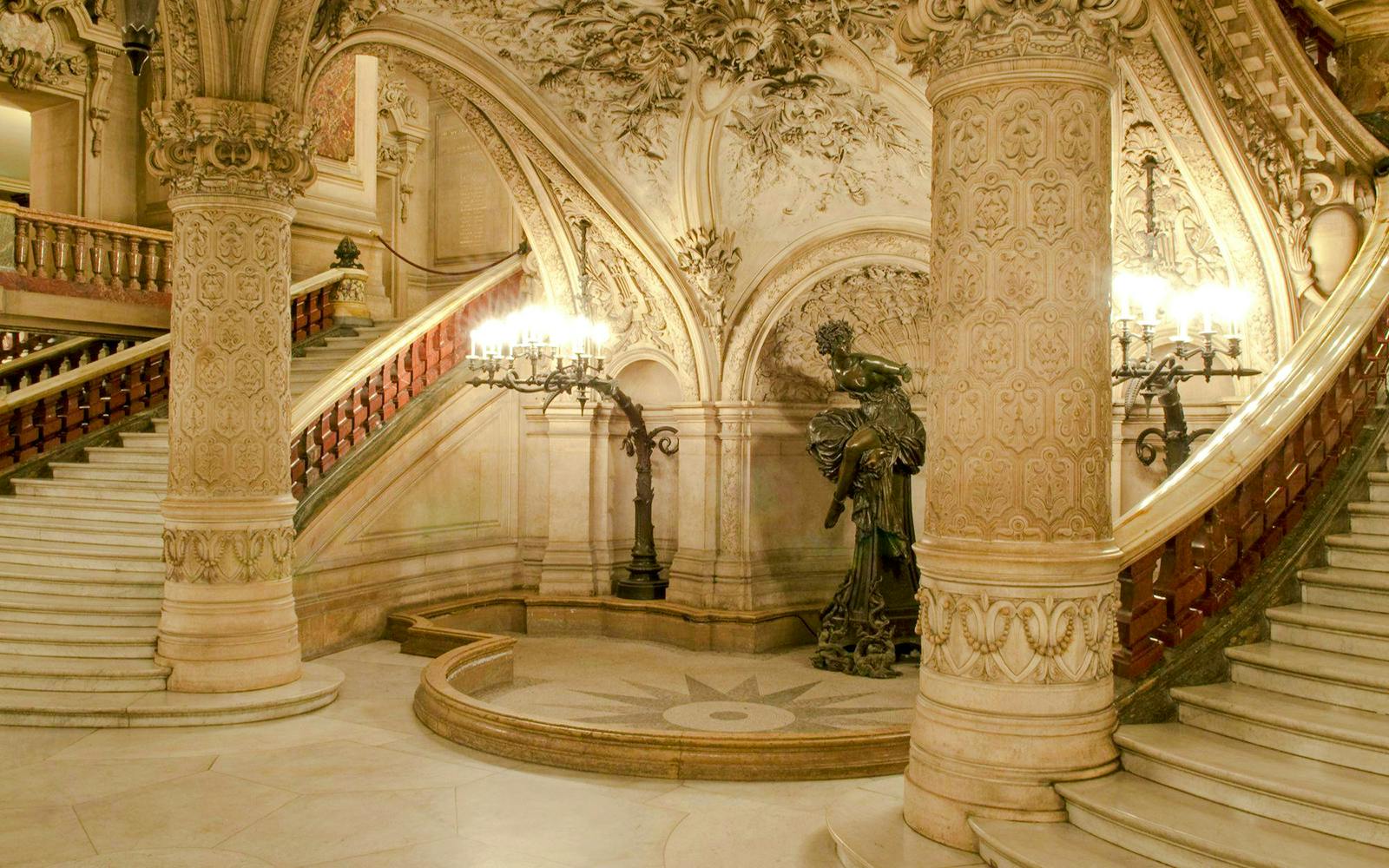 Grand staircase of Opéra Garnier, Paris, with ornate sculptures and intricate architectural details.