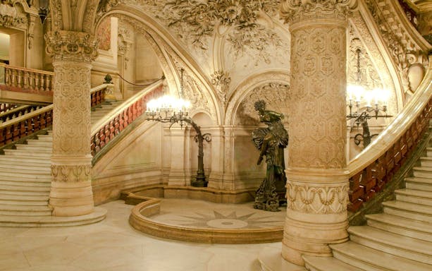 Grand staircase of Opéra Garnier, Paris, with ornate sculptures and intricate architectural details.