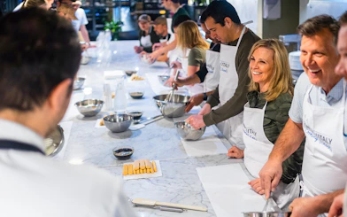 Participants in a cooking class preparing pasta and risotto in Milan.