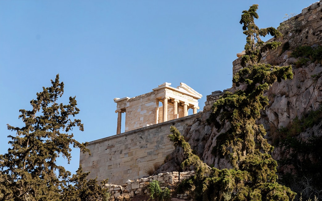 Parthenon temple on the Acropolis hill, Athens, with surrounding trees.