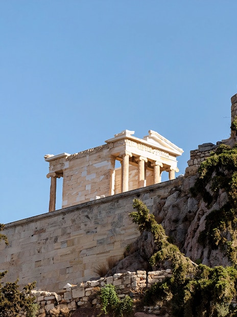 Parthenon temple on the Acropolis hill, Athens, with surrounding trees.
