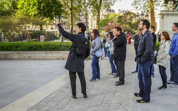 Tour group exploring Île de la Cité, Paris, with guide pointing out landmarks.