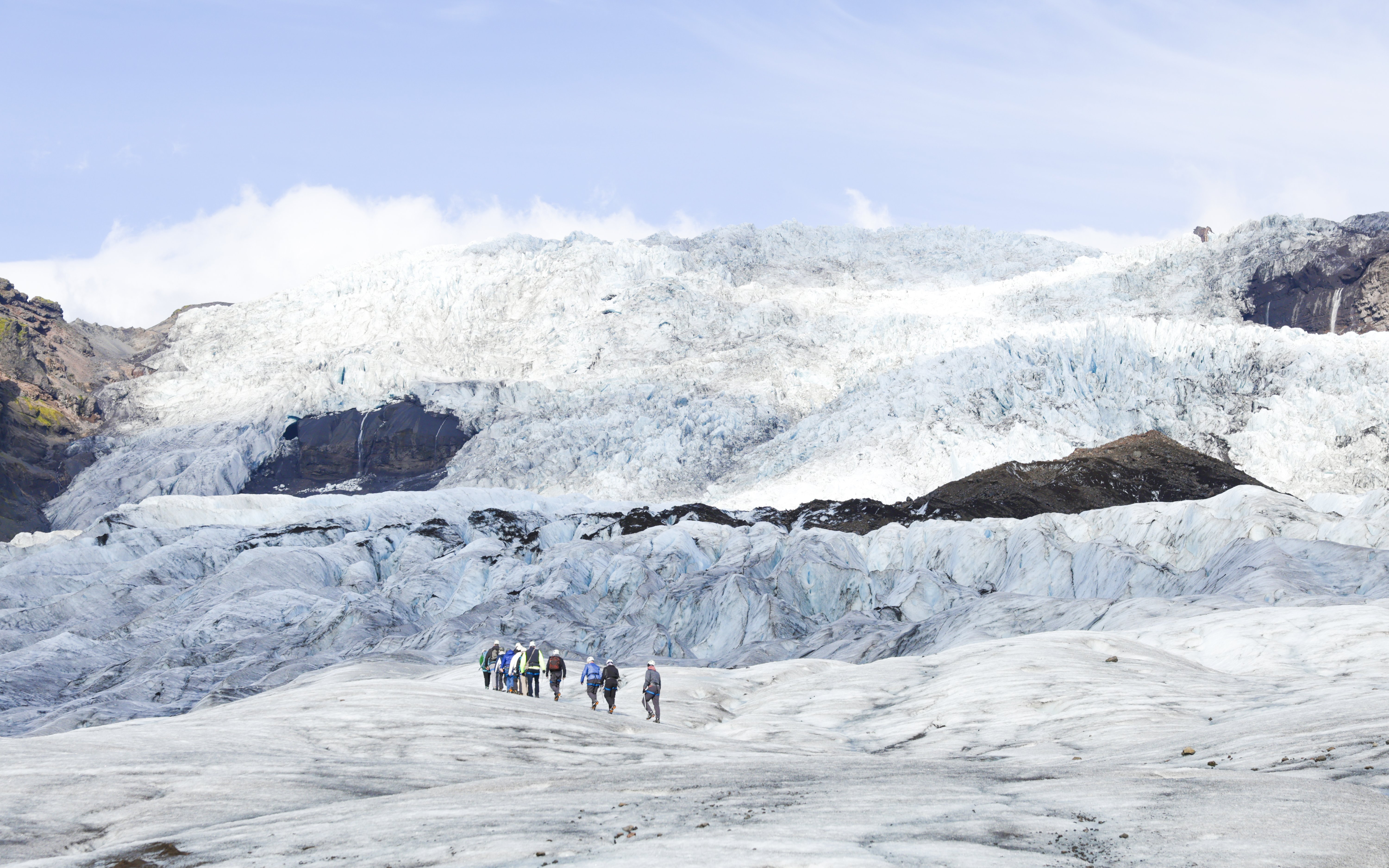 Hikers with backpacks and ice axes on Falljokull glacier in Iceland.