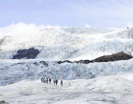 Hikers with backpacks and ice axes on Falljokull glacier in Iceland.