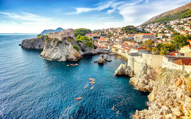 Kayakers near Dubrovnik's historic city walls and rocky coastline.