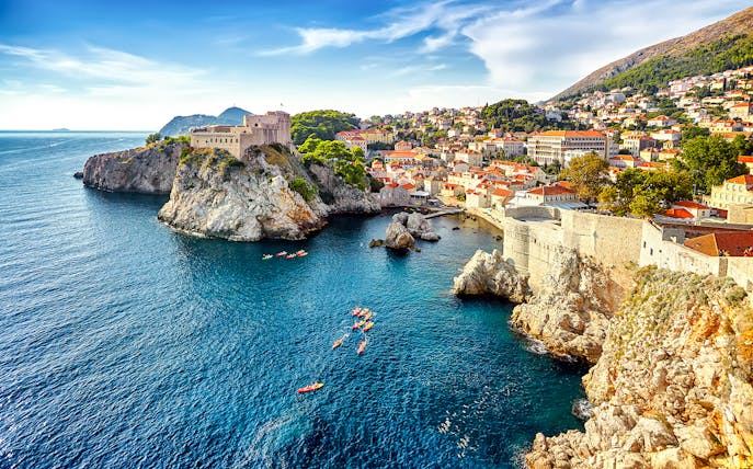 Kayakers near Dubrovnik's historic city walls and rocky coastline.