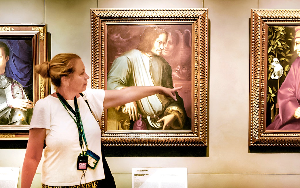 Guide explaining Renaissance painting to group at Uffizi Gallery.