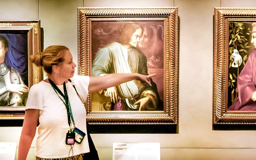 Guide explaining Renaissance painting to group at Uffizi Gallery.