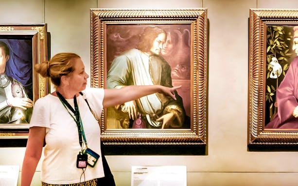 Guide explaining Renaissance painting to group at Uffizi Gallery.