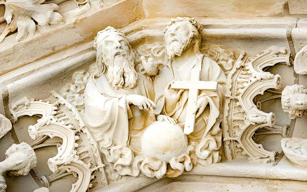 Stone carvings at Château de Vincennes depicting two figures with a cross and globe.