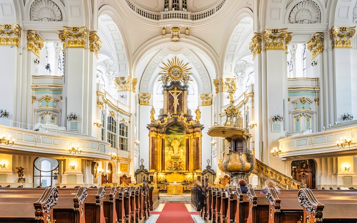 Interior of St. Michael's Church in Hamburg, featuring ornate altar and pews.